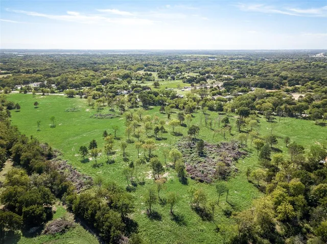 an aerial view of residential houses with outdoor space and trees