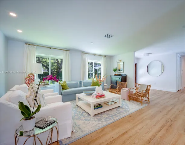 a living room with furniture couches and a dining table with wooden floor