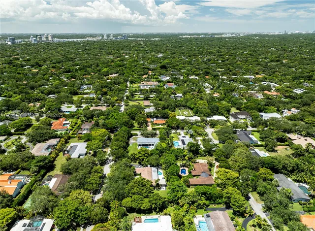 an aerial view of residential houses with outdoor space and trees