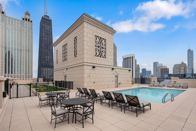 10 East Delaware Place, Unit 12E Chicago, IL 60611 - Photo 19 of 25 a view of a patio with table and chairs with barbeque grill and wooden fence