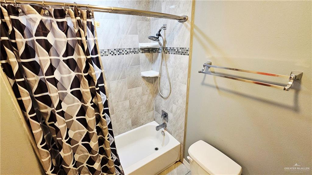 4711 North Stewart Road Palmhurst, TX 78573 - Photo 21 of 40 a bathroom with a shower curtain and a toilet