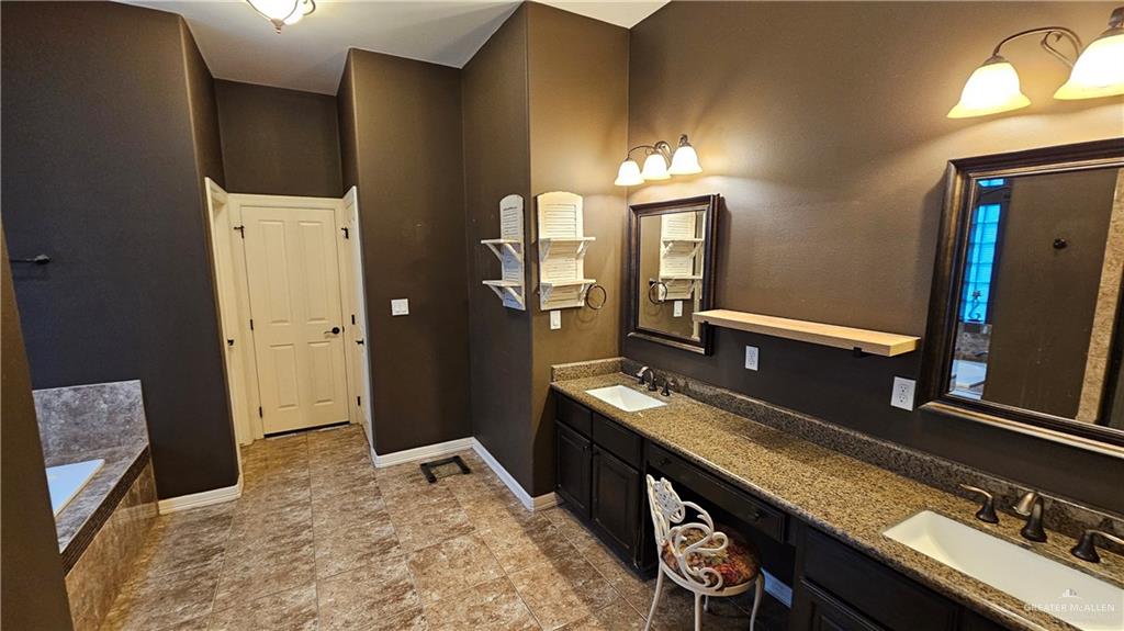 4711 North Stewart Road Palmhurst, TX 78573 - Photo 30 of 40 a en suite bathroom with a granite countertop sink and a mirror