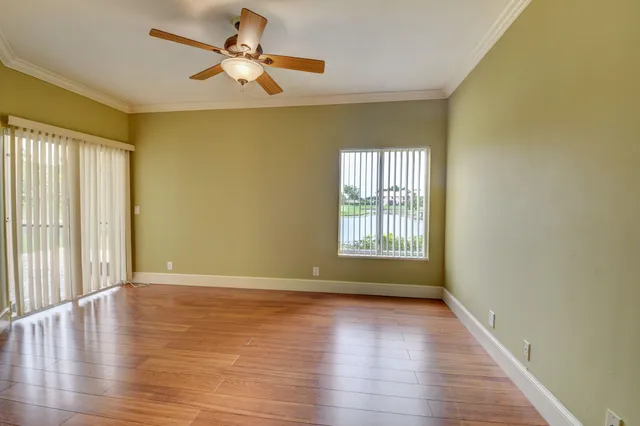 an empty room with wooden floor closet and windows