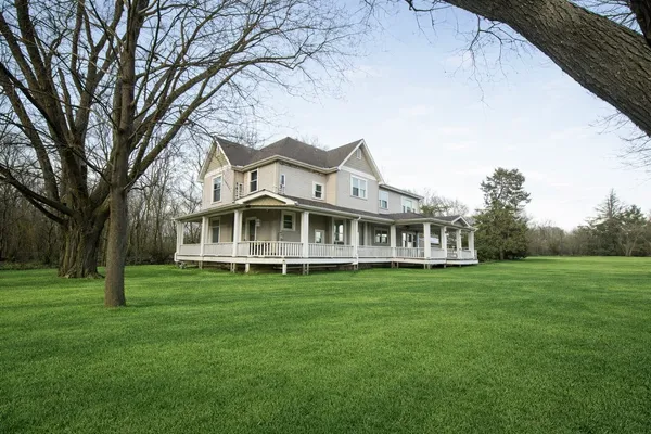 a white house with a big yard and large trees