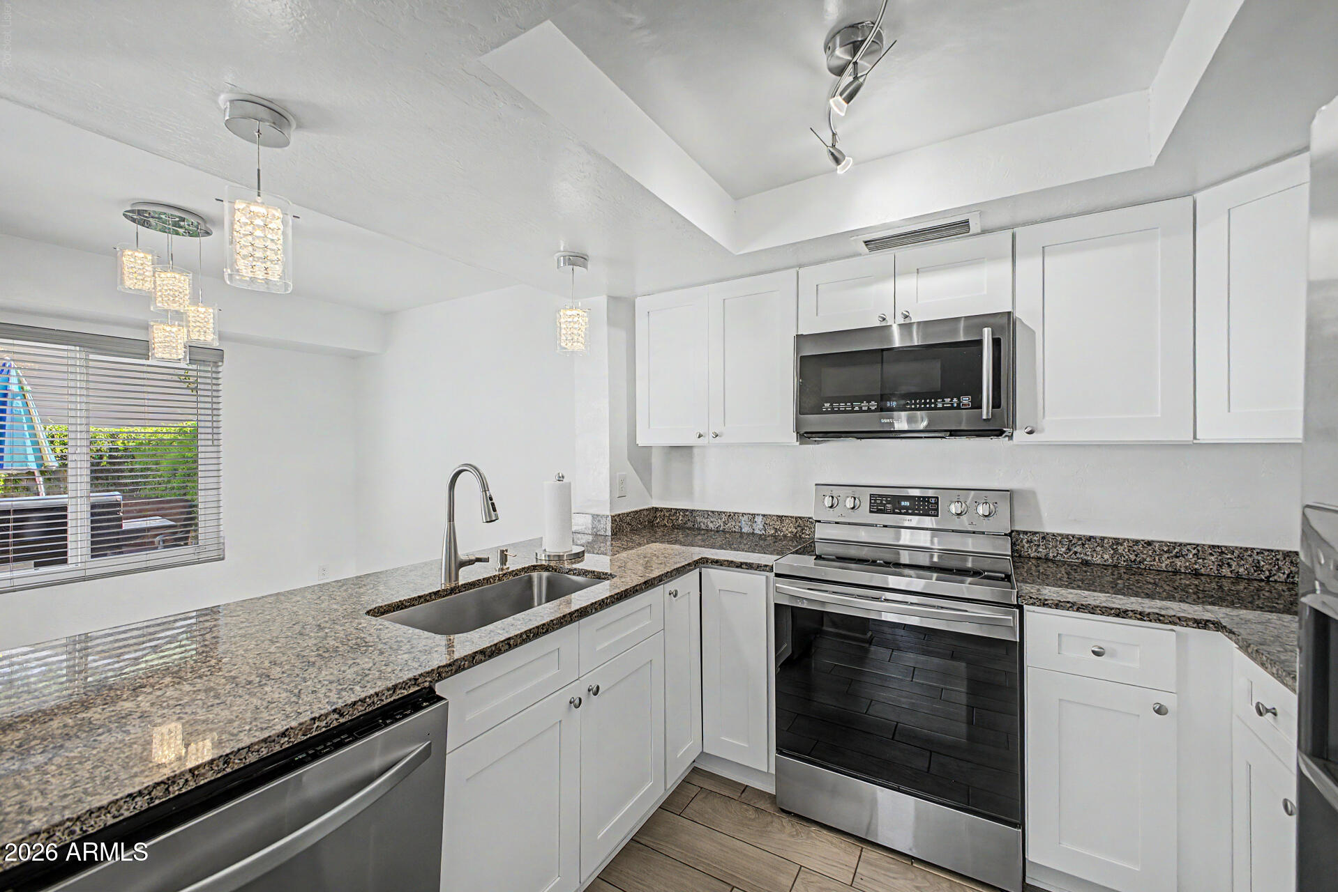 2455 East Broadway Road, Unit 103 Mesa, AZ 85204 - Photo 7 of 22 a kitchen with granite countertop a sink stainless steel appliances and white cabinets