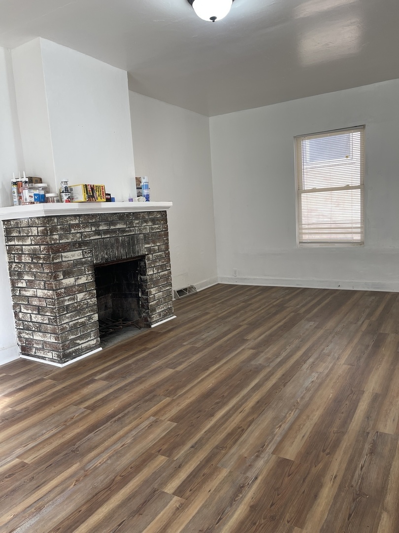 271 East 148th Street Harvey, IL 60426 - Photo 2 of 7 a view of an empty room with wooden floor and a fireplace