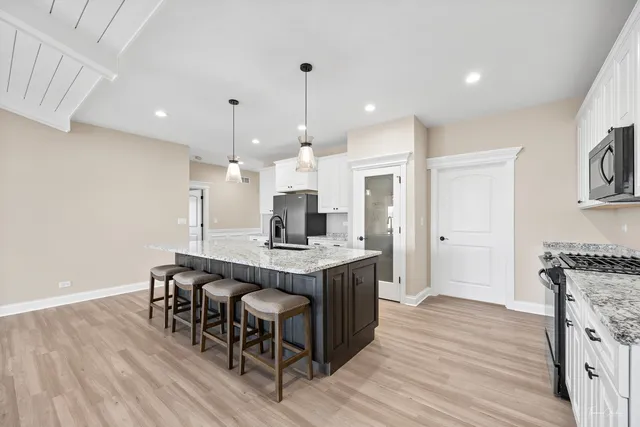 a kitchen with stainless steel appliances granite countertop a table chairs stove a sink and a refrigerator