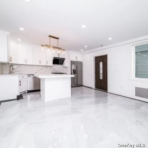 a view of a kitchen with kitchen island a sink stainless steel appliances and cabinets