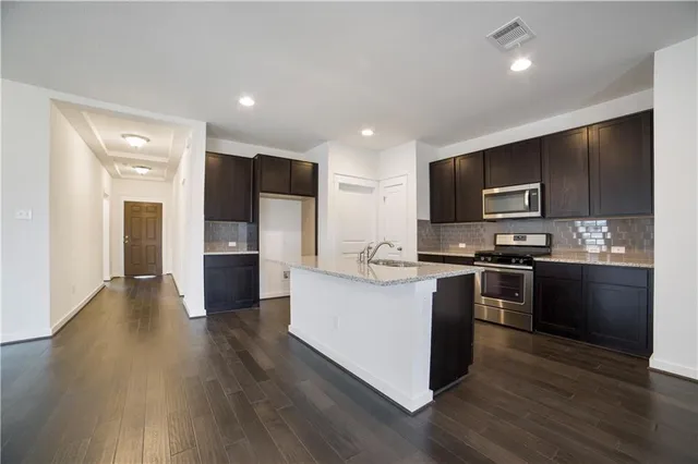 a large kitchen with stainless steel appliances and wooden floors