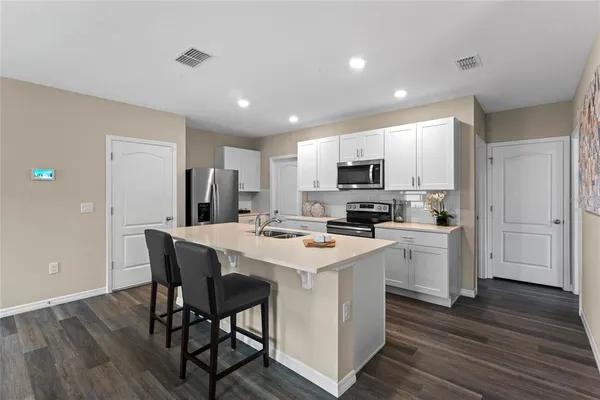 a kitchen with a sink a microwave a refrigerator and cabinets
