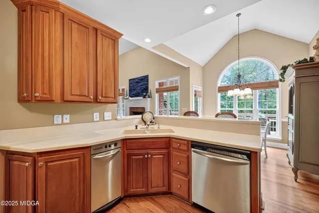 a kitchen with stainless steel appliances granite countertop a sink a stove and a wooden floors