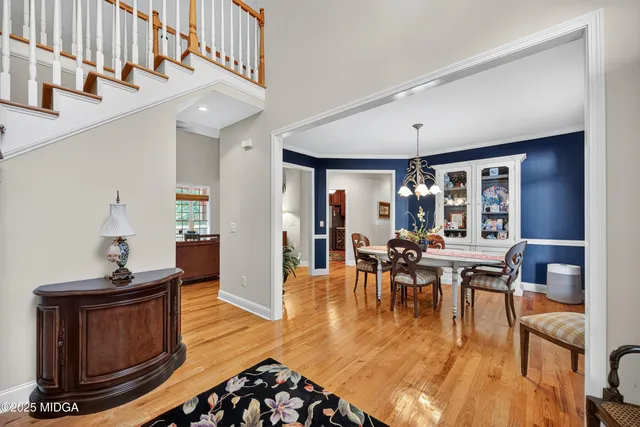 a dining room with wooden floor a chandelier a wooden table and chairs