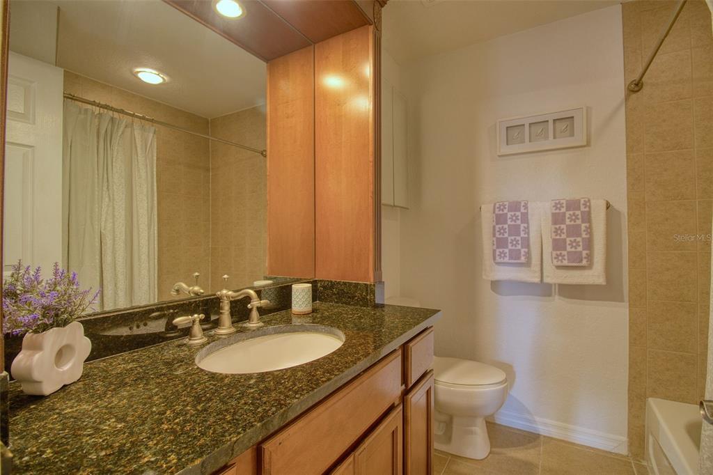 702 Lyndhurst Street, Unit 821 Dunedin, FL 34698 - Photo 12 of 30 a bathroom with a granite countertop sink and a mirror with toilet