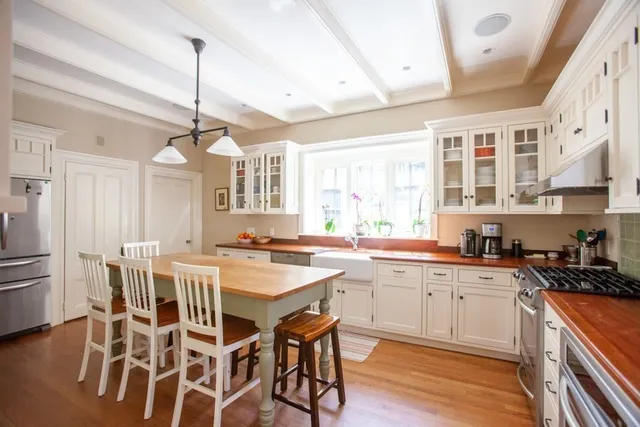 a kitchen with stainless steel appliances a center island wooden floor and a window
