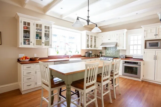 a kitchen with stainless steel appliances kitchen island granite countertop a stove a refrigerator a kitchen island with a stove and white cabinets