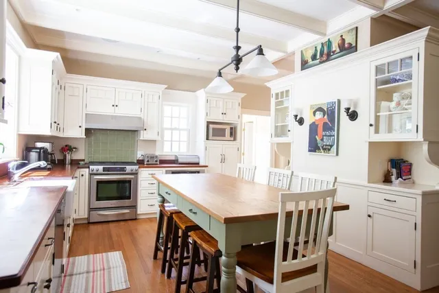 a kitchen with stainless steel appliances granite countertop a stove top oven a sink a dining table and chairs with wooden floor