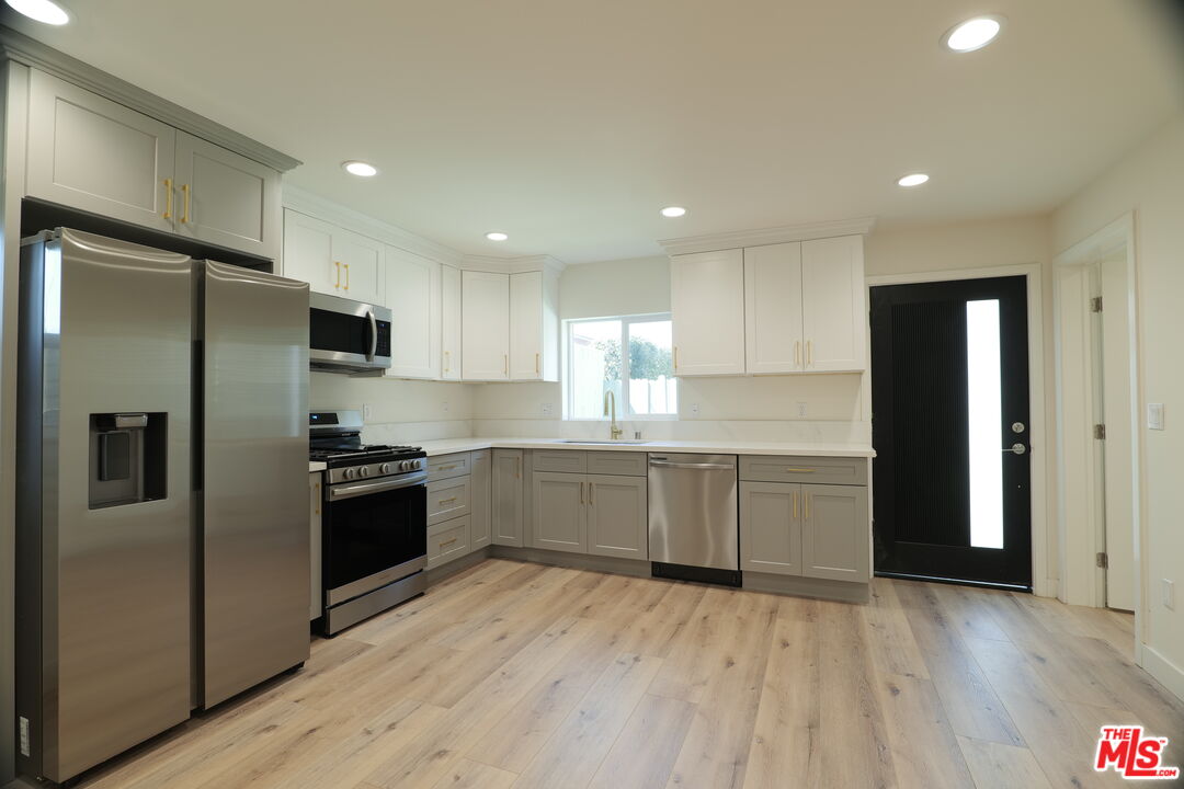 1338 West 30th Street Los Angeles, CA 90007 - Photo 2 of 21 a kitchen with granite countertop a refrigerator and a stove top oven