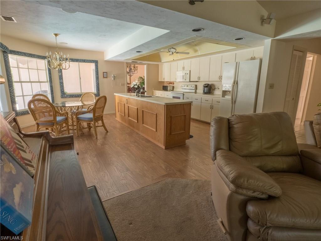 501 Springline Drive Naples, FL 34102 - Photo 6 of 14 a living room with couches a coffee table and kitchen view with wooden floor