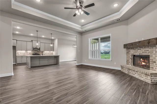 a view of an empty room with a kitchen and a window