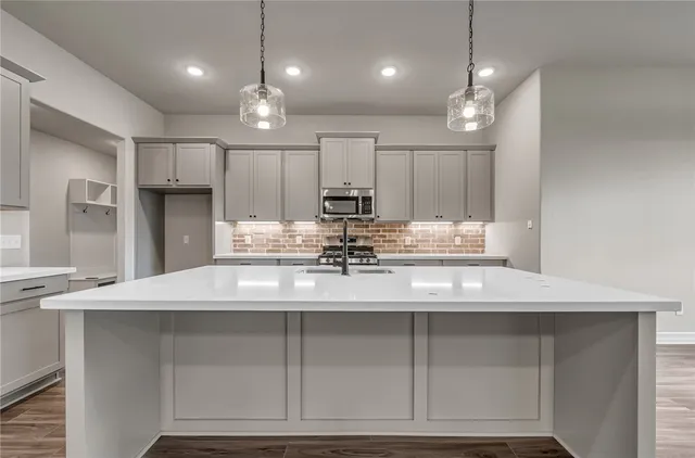 a kitchen with kitchen island granite countertop a sink cabinets and stainless steel appliances