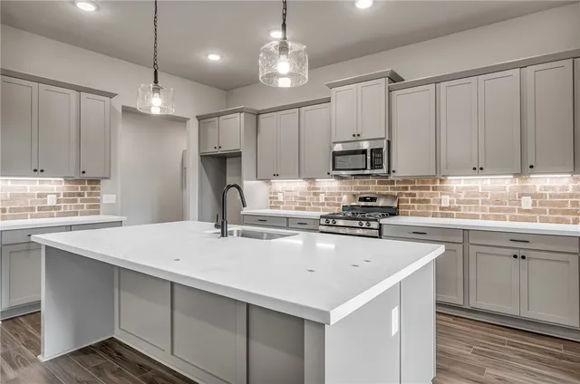 a kitchen with kitchen island a sink stainless steel appliances and cabinets