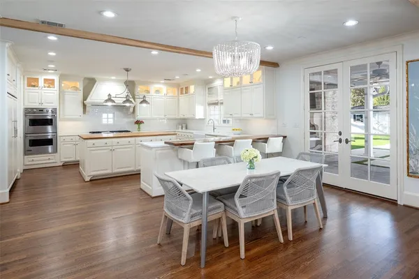 a kitchen with stainless steel appliances a dining table chairs and wooden floor