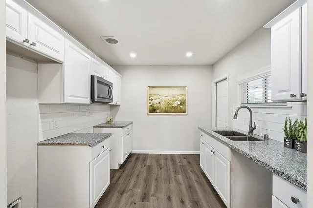 a kitchen with granite countertop a sink stainless steel appliances and white cabinets