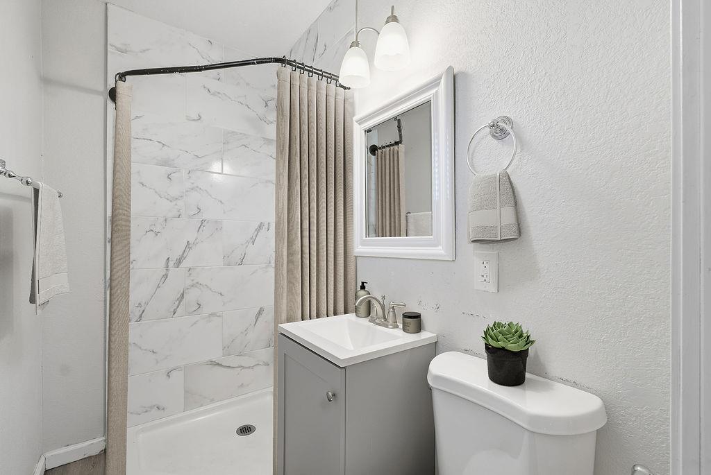2999 East Richert Avenue Fresno, CA 93726 - Photo 7 of 19 a bathroom with a granite countertop sink a toilet and shower