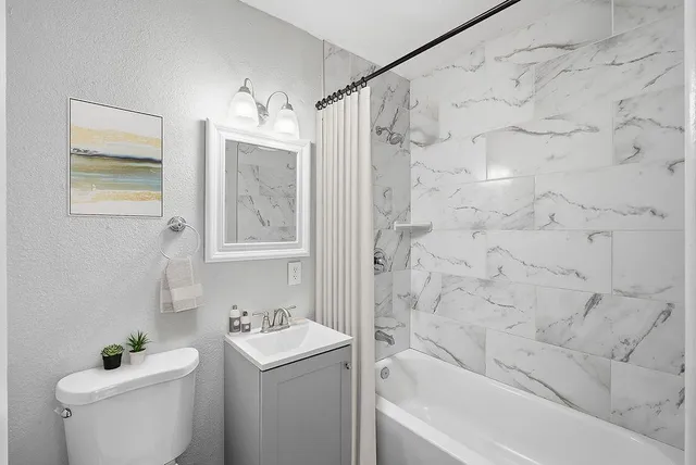 a bathroom with a granite countertop sink a toilet and shower