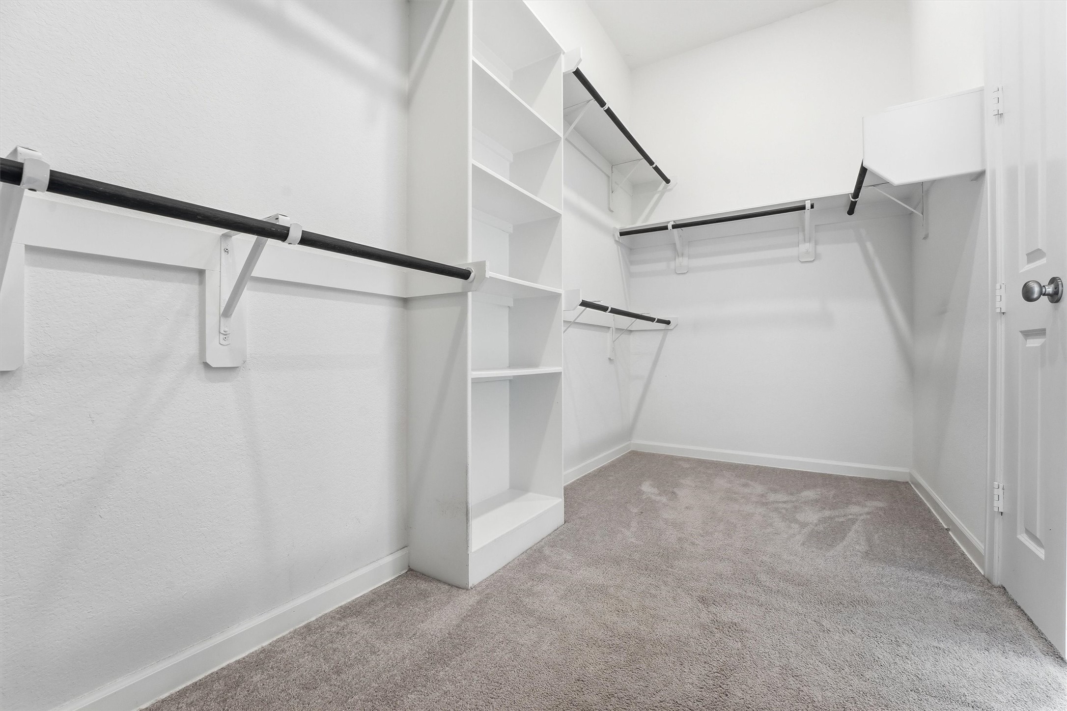 6071 Windward Falls Way Porter, TX 77365 - Photo 21 of 33 Spacious walk-in closet with ample shelving and hanging space, featuring carpeted flooring and a clean, white finish.