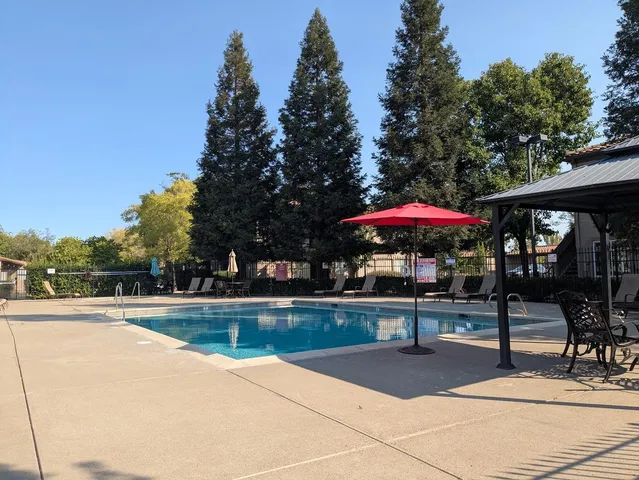 a view of a swimming pool with a table and chairs under an umbrella