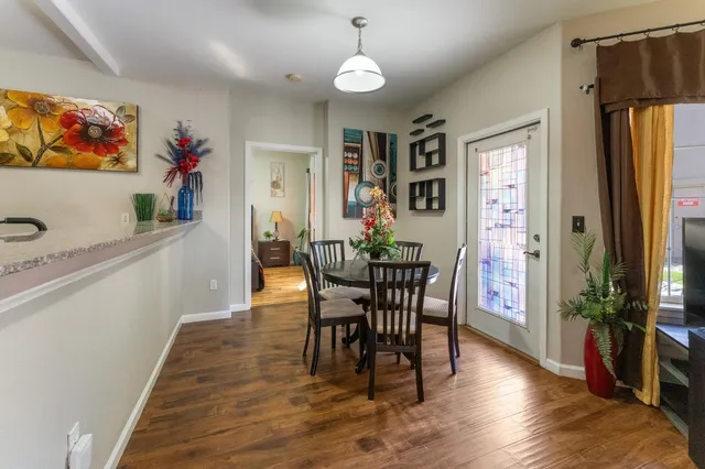 a dining room with wooden floor a chandelier a wooden table and chairs