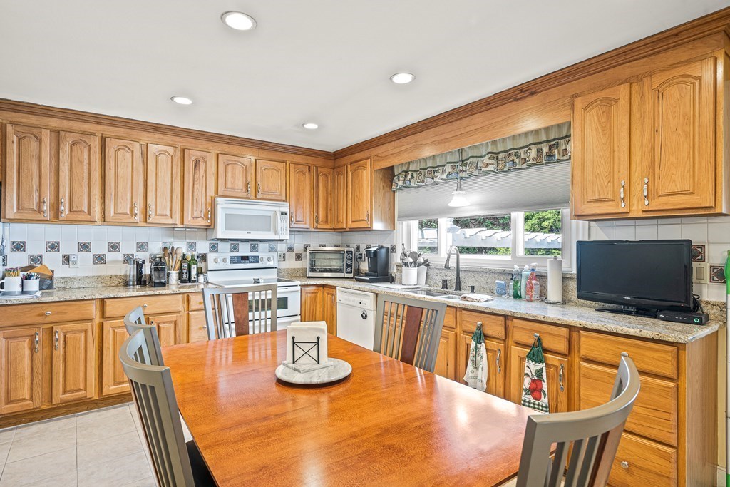 23 Webster Road Lexington, MA 02421 - Photo 2 of 32 a kitchen with stainless steel appliances granite countertop a stove top oven a sink a dining table and chairs with wooden floor