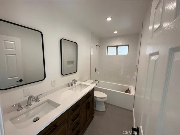 a bathroom with a double vanity sink toilet mirror and bathtub