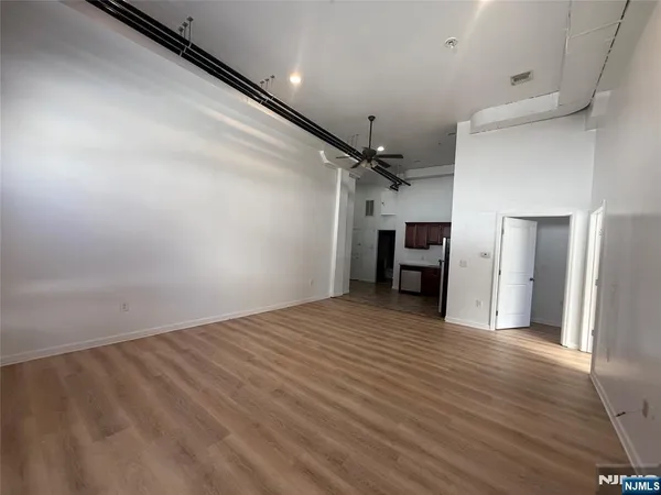 an empty room with wooden floor ceiling fan and windows
