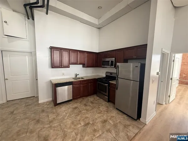 a kitchen with granite countertop a refrigerator and a stove top oven