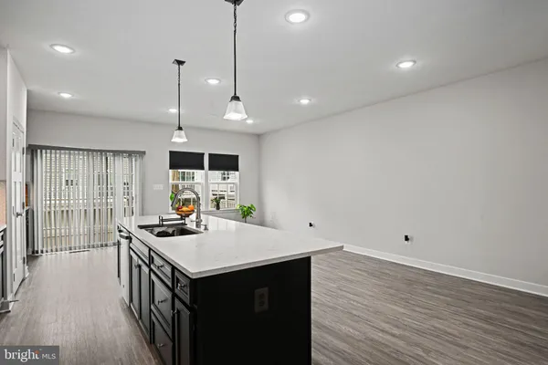 a kitchen with a stove a sink a refrigerator and wooden floor