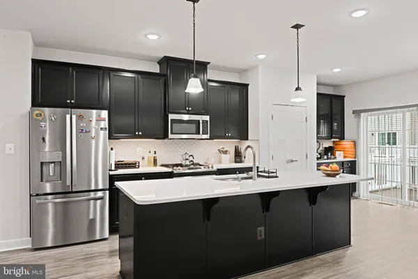 a kitchen with stainless steel appliances a sink a refrigerator a center island a stove and cabinets