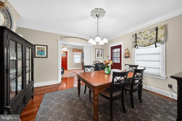 a dining room with wooden floor a chandelier a wooden table and chairs