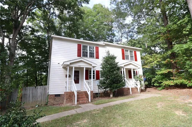 a front view of a house with a yard and trees