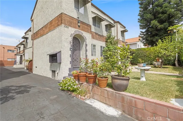 a view of a white house with potted plants and a lawn chairs