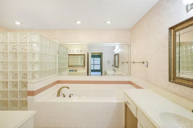 a bathroom with a tub sink and mirror