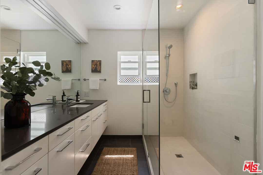5719 Rhodes Avenue Valley Village, CA 91607 - Photo 40 of 55 a bathroom with a double vanity sink a large mirror a bathtub and shower