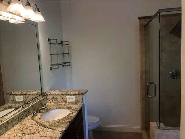 a bathroom with a granite countertop sink toilet and shower