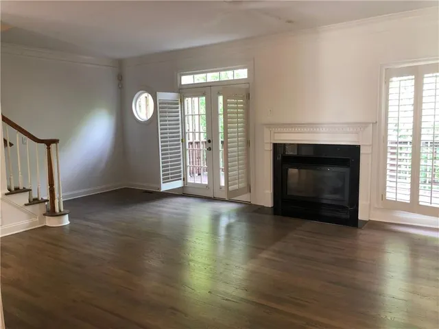 an empty room with wooden floor fireplace and windows