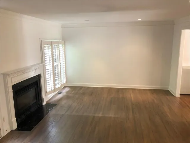 an empty room with wooden floor fireplace and windows