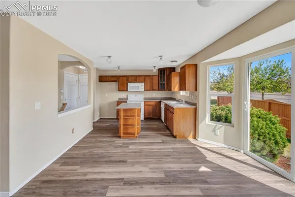 a kitchen with stainless steel appliances granite countertop a sink and wooden cabinets with wooden floors