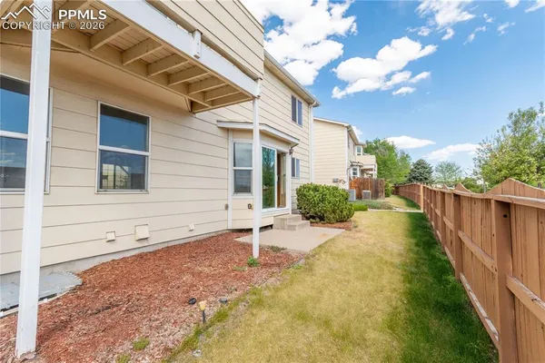 a view of a house with backyard and wooden fence