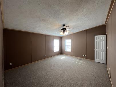 99 Roots Road Martindale, TX 78655 - Photo 16 of 28 Carpeted empty room featuring a ceiling fan and a decorative wall