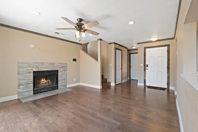 a view of an empty room with wooden floor fireplace and a window